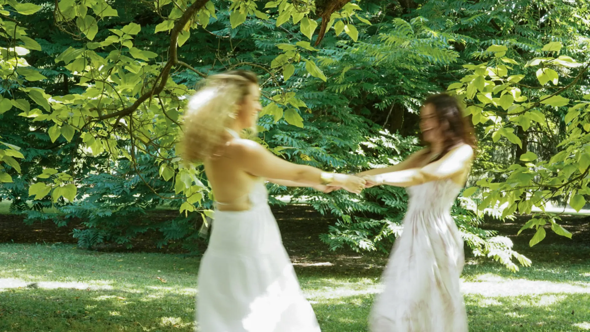 Alja and Eva, the two sisters behind Dobro počutje, spinning together in a green meadow